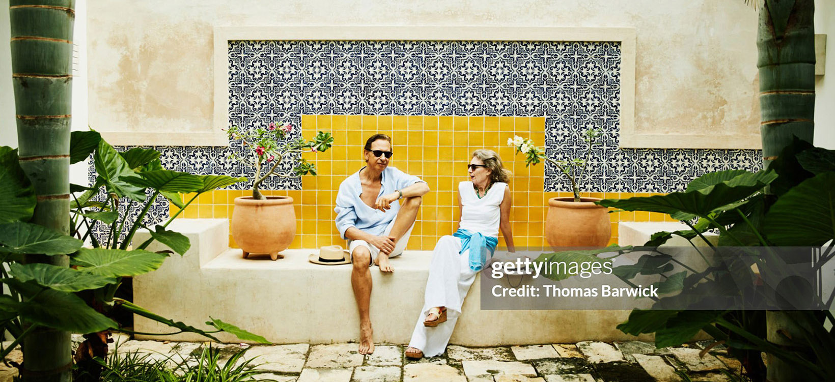 Senior couple relaxing in courtyard at tropical resort.
