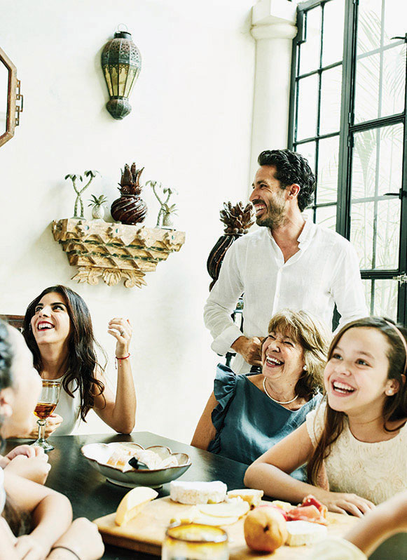 Laughing multigenerational family gathered around dining room table.