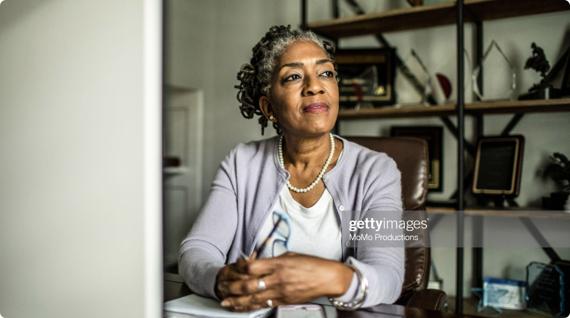 Black businesswoman sitting at desk in home office looking thoughtful.