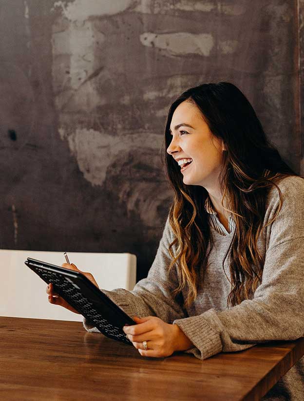 Woman sitting at table holding tablet