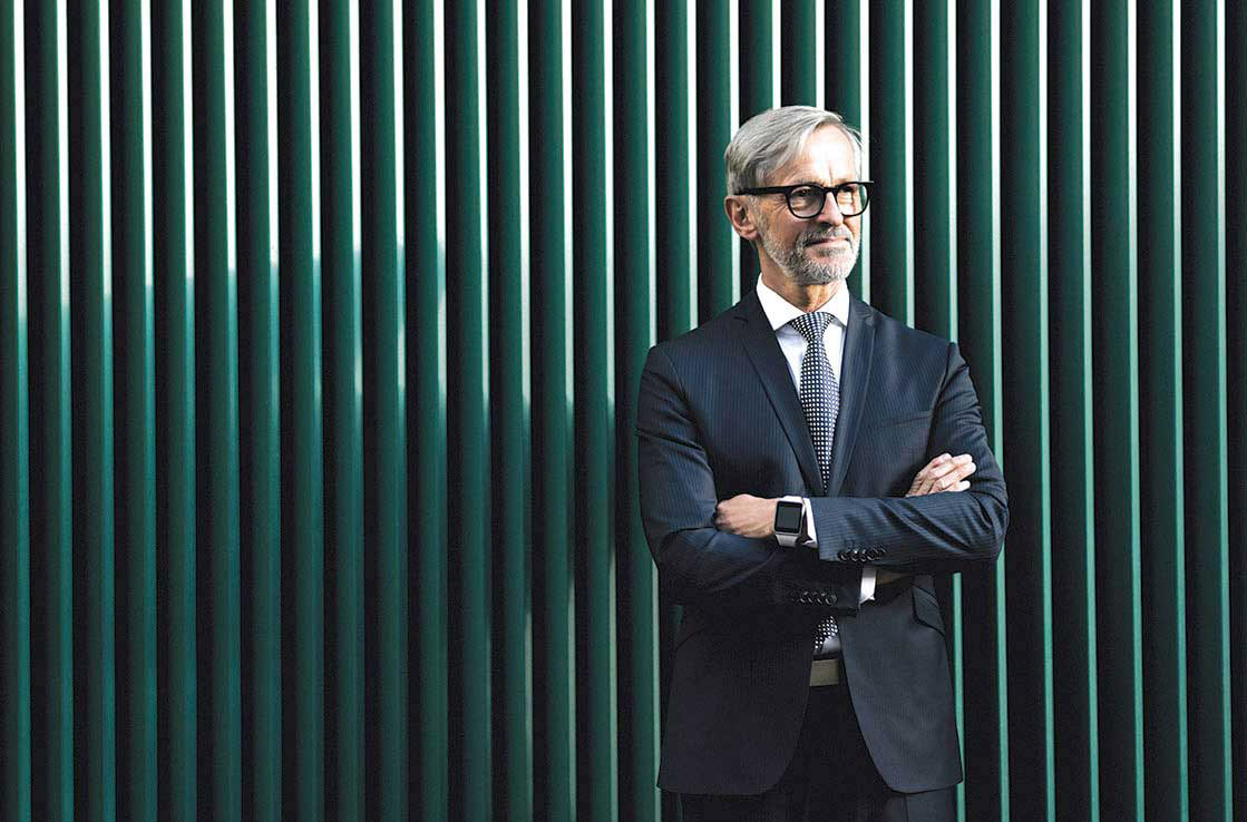 Businessman with arms crossed standing in front of striped wall.