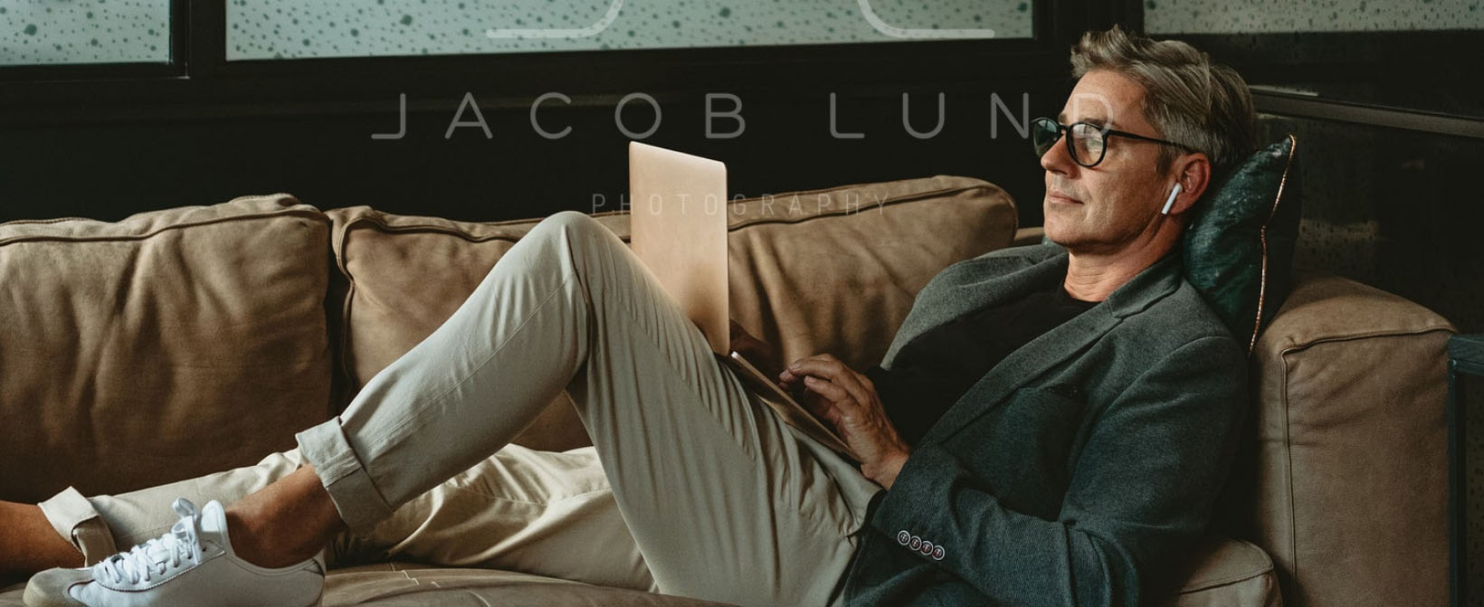 Businessman lying on the sofa working on laptop.