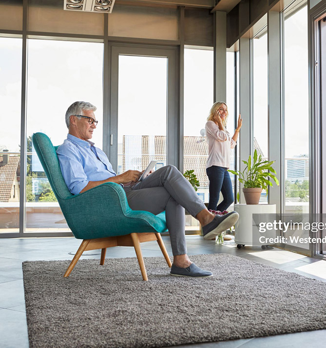 Mature couple relaxing at home using tablet and cell phone.