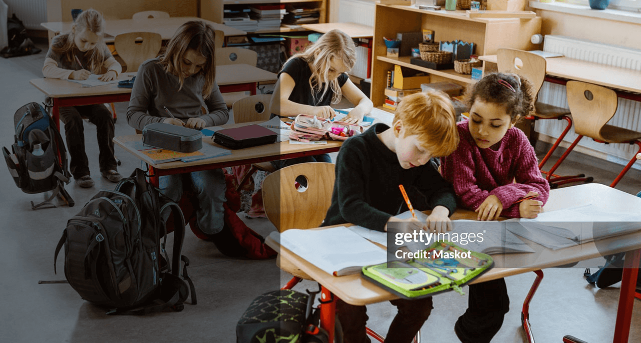 Male and female students studying together sitting at desk in classroom.