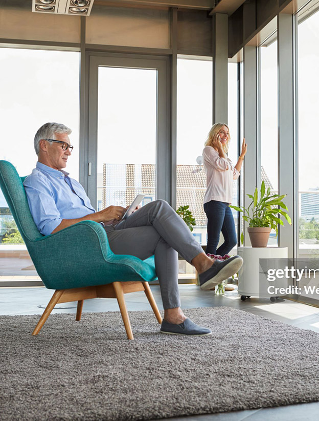 Mature couple relaxing at home using tablet and cell phone.
