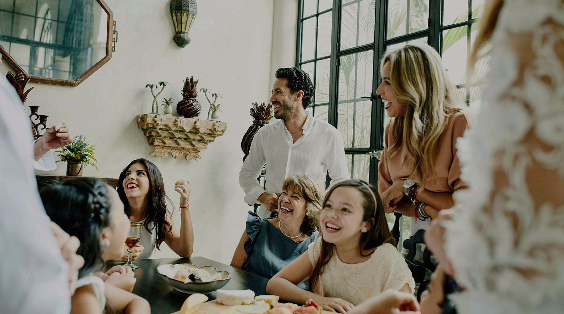 Laughing multigenerational family gathered around dining room table.